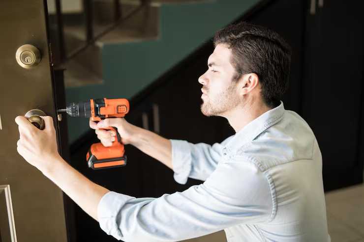Slotenmaker monteert deurbeslag met een accuboormachine